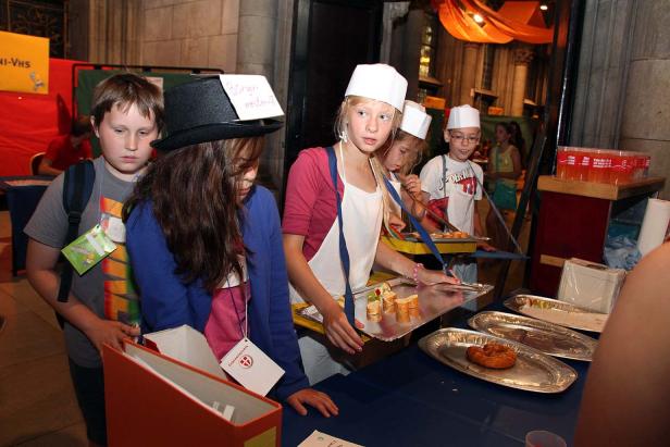 Eine Gruppe Kinder steht an einem Tisch und bereitet Speisen zu.