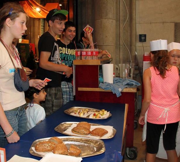 Eine Gruppe von Jugendlichen steht an einem Stand mit Speisen und Getränken.