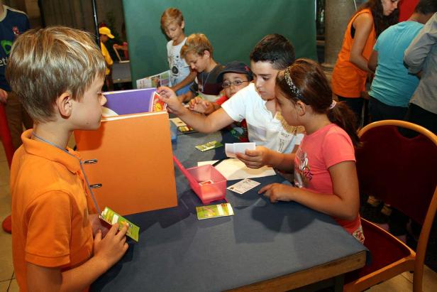 Eine Gruppe Kinder sitzt an einem Tisch und spielt ein Kartenspiel.