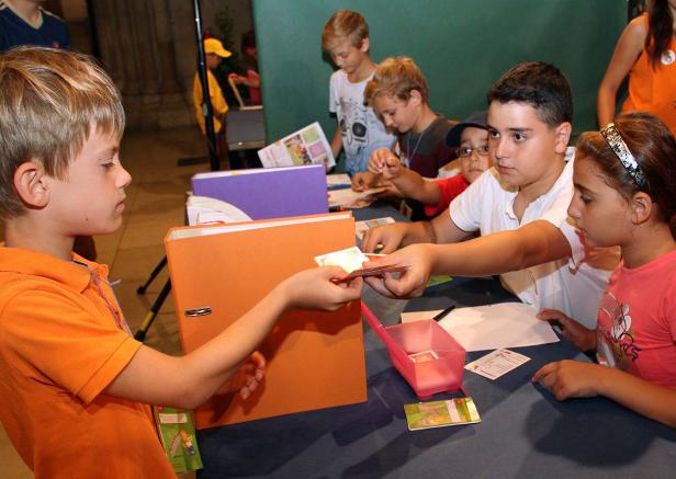 Eine Gruppe Kinder tauscht Karten an einem Tisch aus.