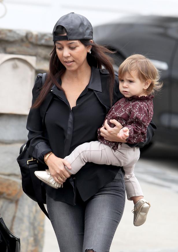 Kourtney Kardashian trägt ihr Kind auf dem Arm.