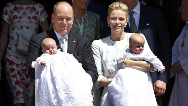 Fürst Albert und Fürstin Charlène von Monaco halten ihre Zwillinge in weißen Taufkleidern.