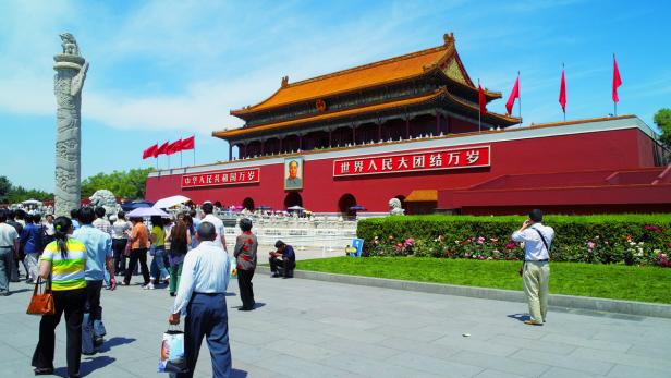 Die Tiananmen-Platz in Peking mit Menschen und der markanten Architektur im Hintergrund.