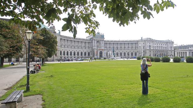 Eine Frau fotografiert die Hofburg in Wien.