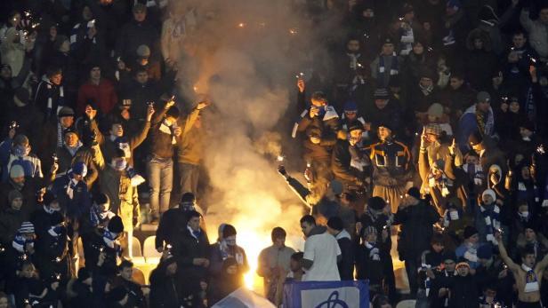 Eine Menschenmenge zündet Feuerwerkskörper und Bengalos in einem Stadion.