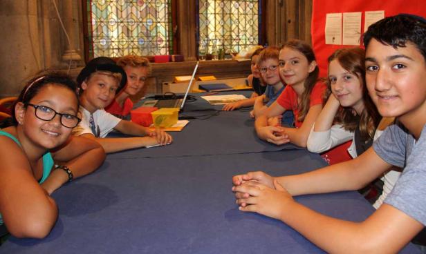 Eine Gruppe von Kindern sitzt an einem Tisch und lächelt in die Kamera.