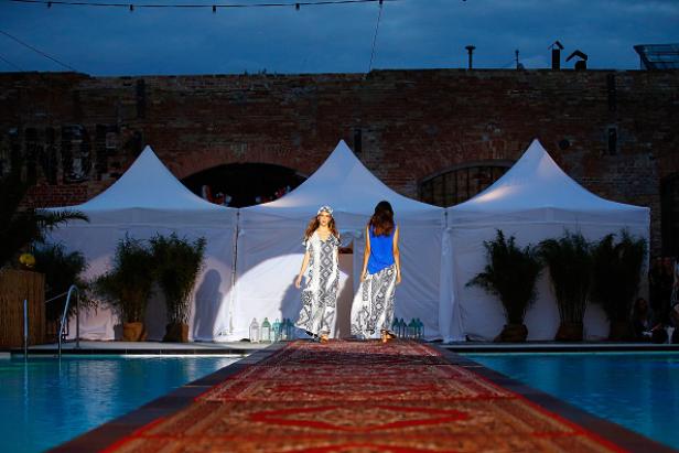 Zwei Models präsentieren Mode auf einem Laufsteg über einem Pool.