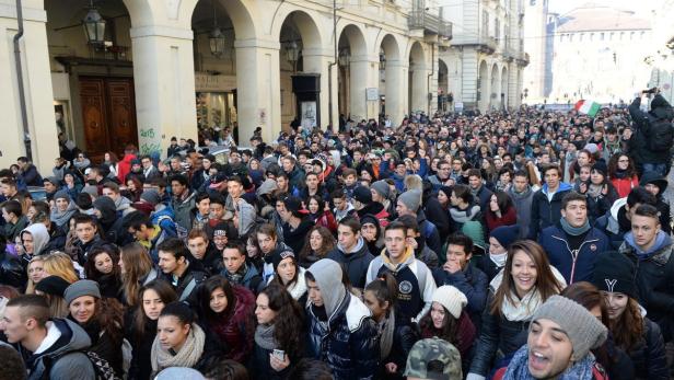 Eine große Menschenmenge versammelt sich auf einer Straße mit Arkaden.