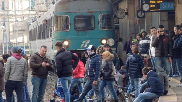 Eine Menschenmenge wartet auf einem Bahnsteig vor einem Zug.