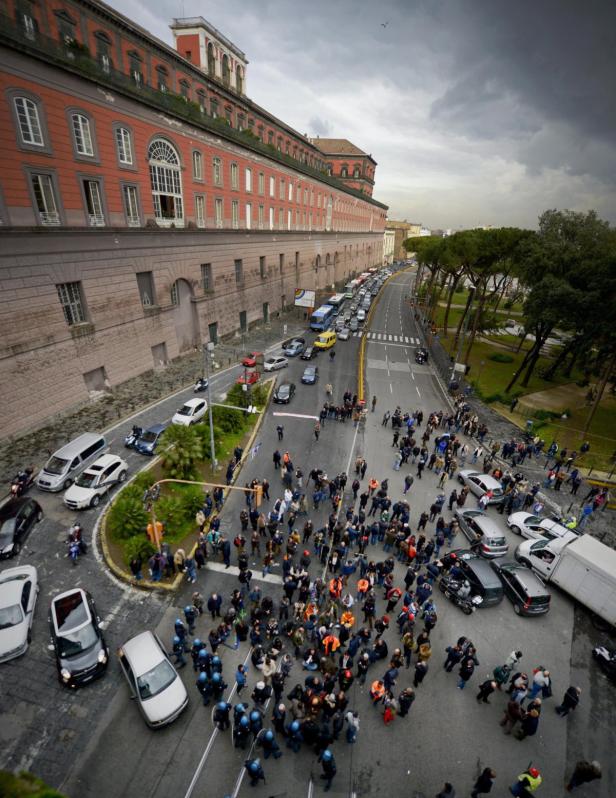 Eine Menschenmenge demonstriert auf einer Straße vor einem großen Gebäude.