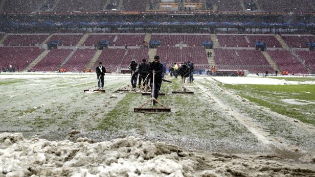 Mitarbeiter räumen Schnee von einem Fußballfeld in einem Stadion.