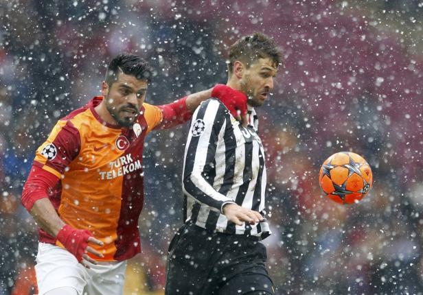 Zwei Fußballspieler kämpfen im Schneefall um den Ball.