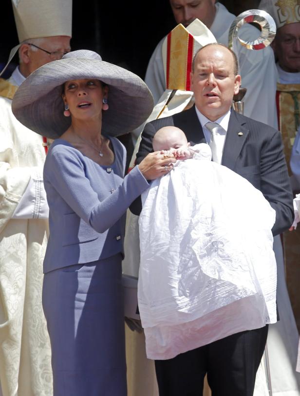Fürst Albert II. von Monaco hält ein Baby, während Fürstin Charlène daneben steht.