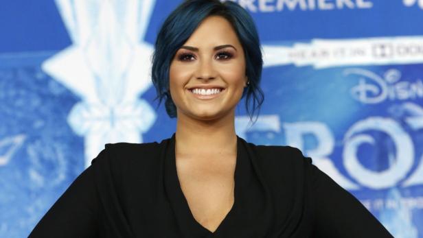 Demi Lovato lächelt vor einem „Frozen“-Werbeplakat.