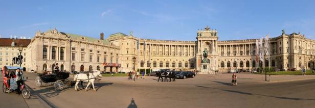 Panorama der Hofburg in Wien mit Kutschen und Passanten.