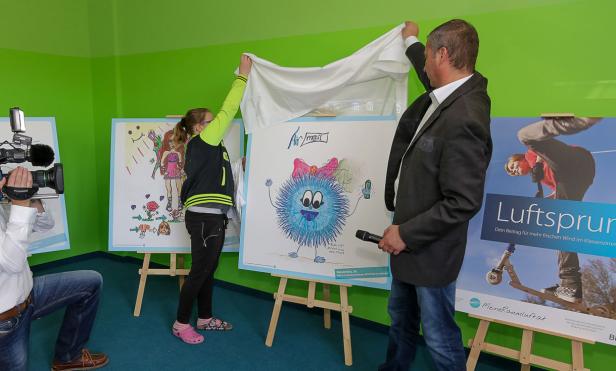 Ein Mädchen und ein Mann enthüllen ein Kinderbild mit der Aufschrift „Airmail“.