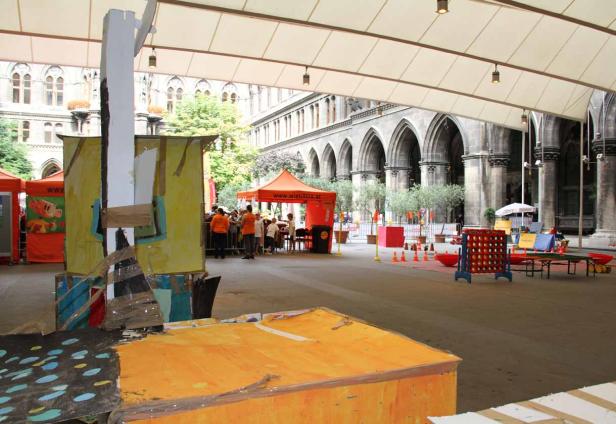 Eine Veranstaltung mit Spielständen und Imbissständen vor einem historischen Gebäude.