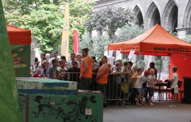 Eine Gruppe von Kindern versammelt sich vor einem Stand von wienXtra.