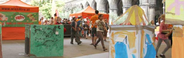 Kinder nehmen an einem Hindernislauf mit bemalten Kartons in der Stadt teil.