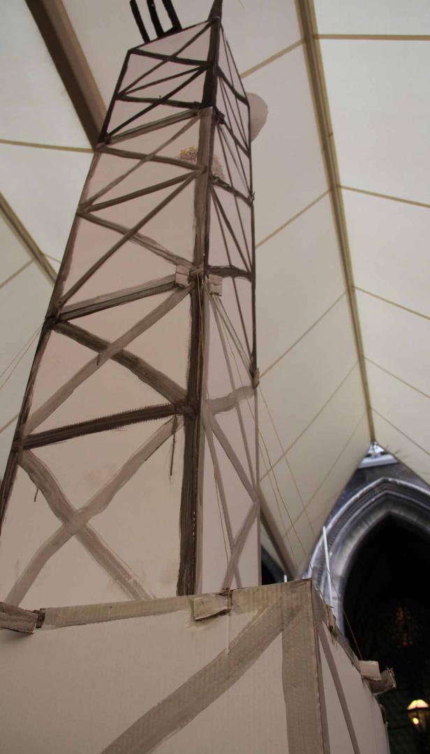 Ein Modell eines hohen Gebäudes mit dunklen Streben unter einem Zeltdach.