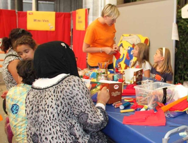 Kinder basteln an einem Tisch mit einer Betreuerin.