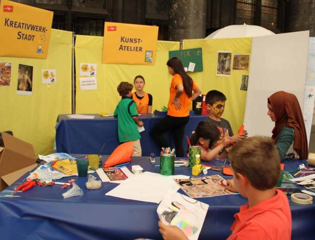 Kinder malen und basteln an einem Stand auf einer Veranstaltung.