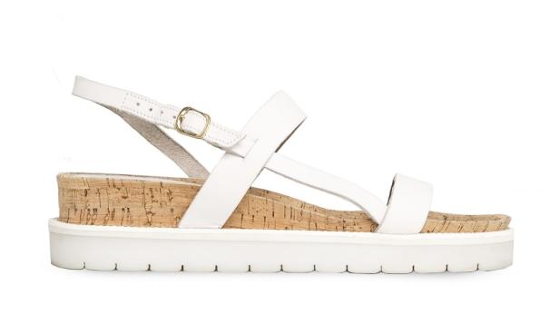 Eine weiße Sandale mit Korksohle und Riemchen steht vor einem weißen Hintergrund.