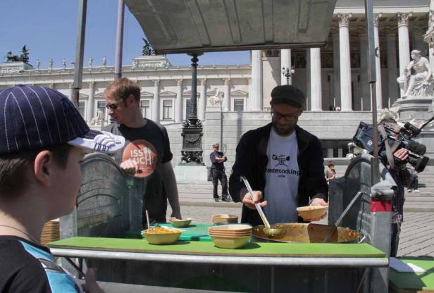 Ein Mann mit Brille serviert Essen an einem Stand vor dem österreichischen Parlament in Wien.