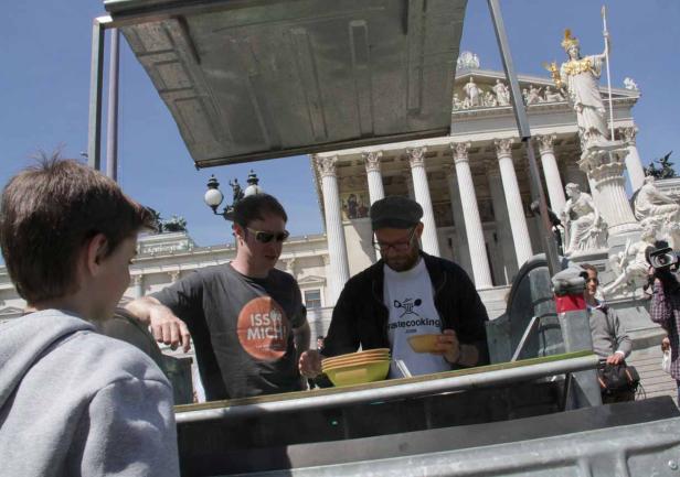 Zwei Männer verteilen Essen vor dem Wiener Parlament.
