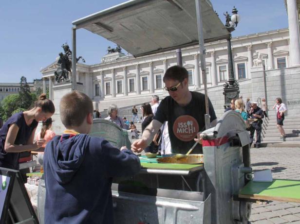 Ein Mann mit Sonnenbrille verkauft Essen an einem Stand vor dem Parlament in Wien.