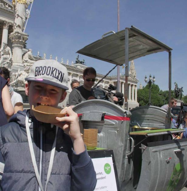 Ein Junge mit einer „Brooklyn“-Kappe isst aus einer Schale vor einem ungewöhnlichen Imbissstand.