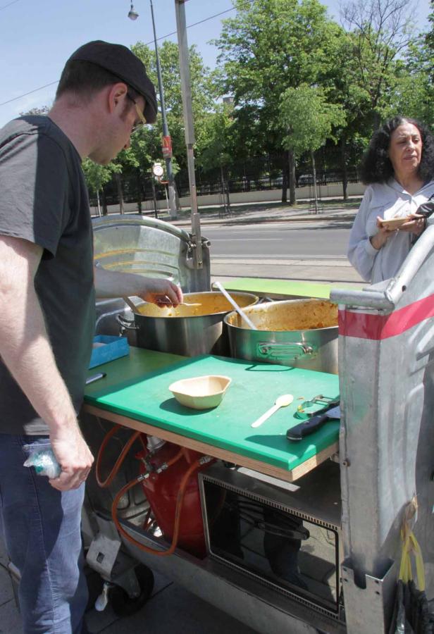 Ein Mann kauft an einem Imbisswagen eine Mahlzeit.