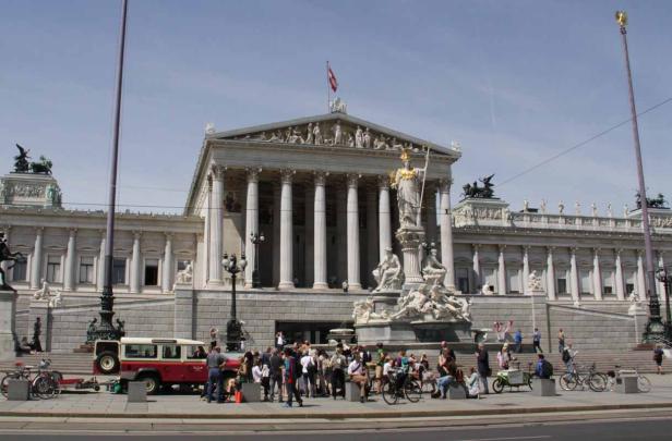 Das österreichische Parlament in Wien mit Menschen davor.