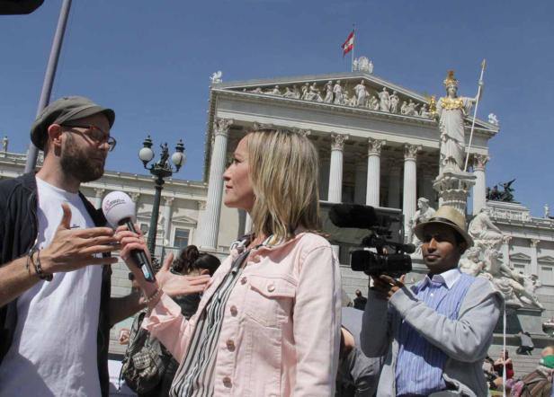 Eine Frau wird vor dem österreichischen Parlament interviewt, während ein Kameramann filmt.
