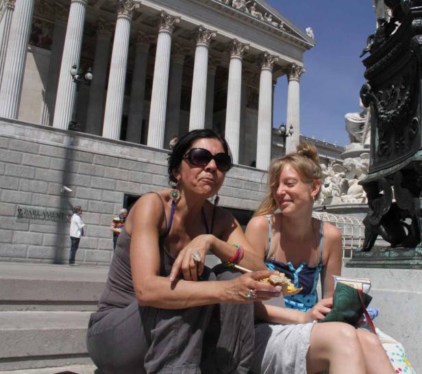 Zwei Frauen sitzen vor dem österreichischen Parlament in Wien und essen.