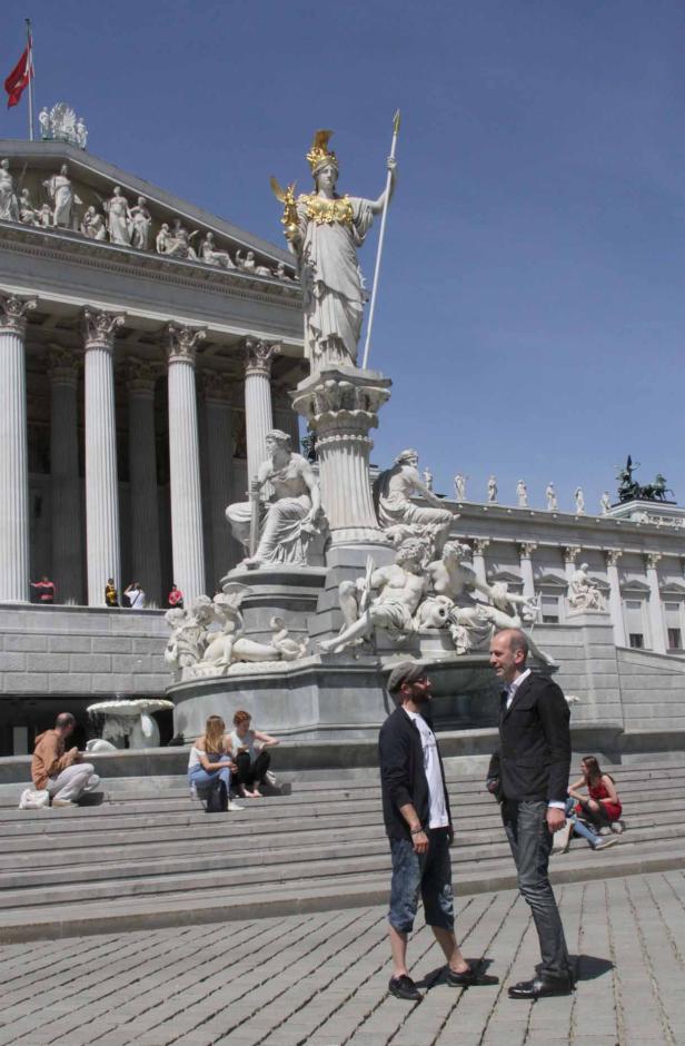 Das österreichische Parlament in Wien mit der Pallas-Athene-Statue und Passanten.