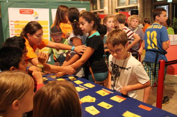 Eine Gruppe Kinder steht an einem Tisch mit gelben Karten.