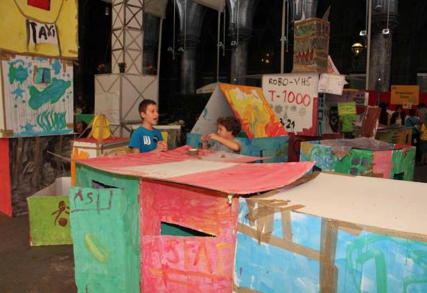 Zwei Jungen spielen in einer bunten Stadt aus Pappkartons.