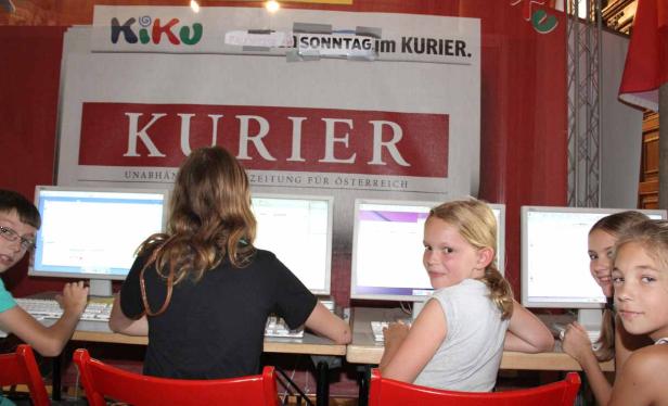 Kinder sitzen vor Computern unter einem „Kurier“-Banner.
