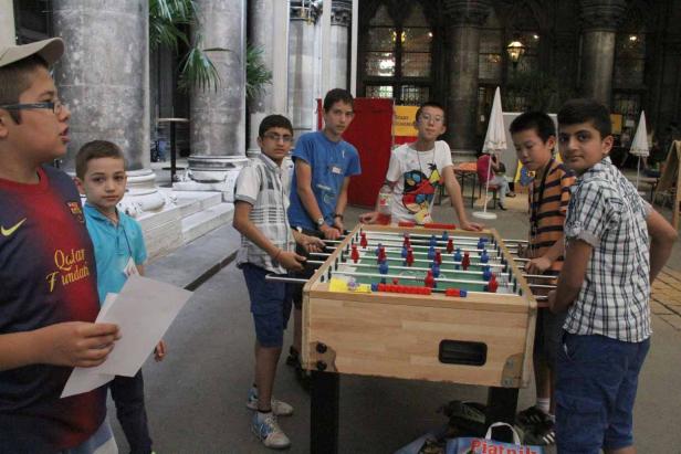 Eine Gruppe von Jungen spielt Tischfußball in einem Innenraum.