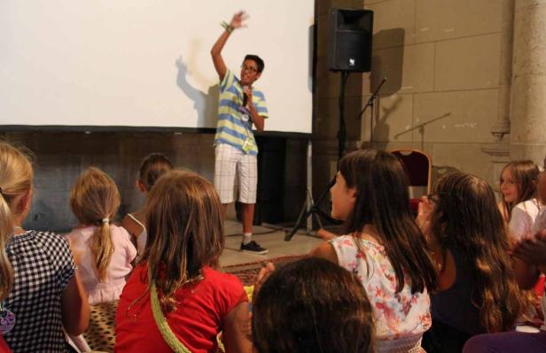 Ein junger Mann hält eine Präsentation vor einer Gruppe von Kindern.