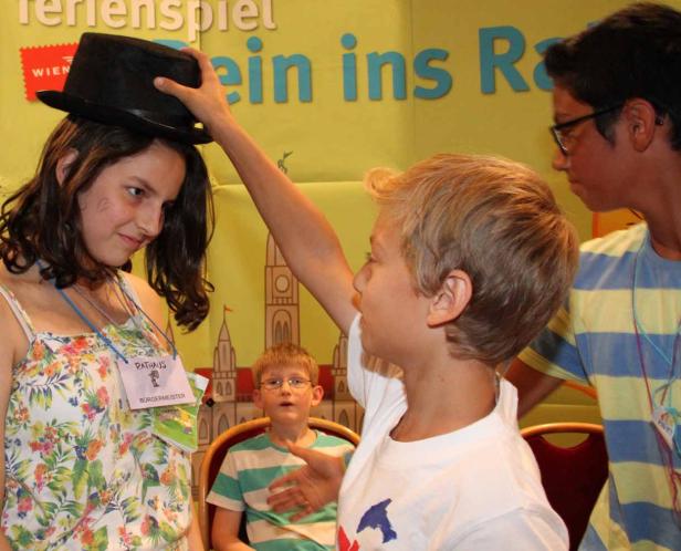 Ein Junge setzt einem Mädchen einen schwarzen Hut auf den Kopf.