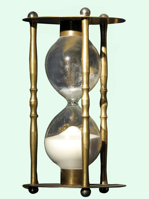 Eine Sanduhr mit goldenem Gestell und weißem Sand.