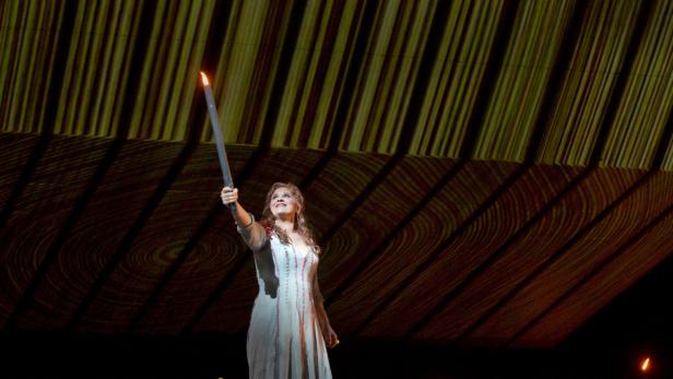 Eine Frau in einem Kleid hält eine Fackel in die Höhe.