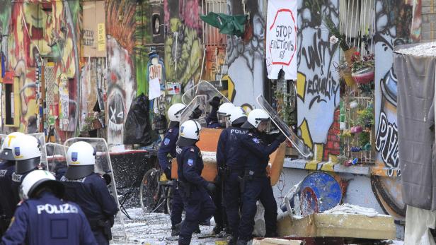 Polizisten räumen ein besetztes Haus mit Graffiti und Protestbannern.