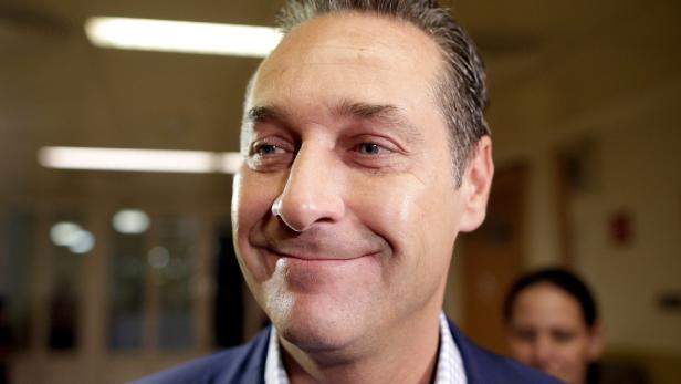 Ein lächelnder Mann in einem blauen Sakko blickt zur Seite.