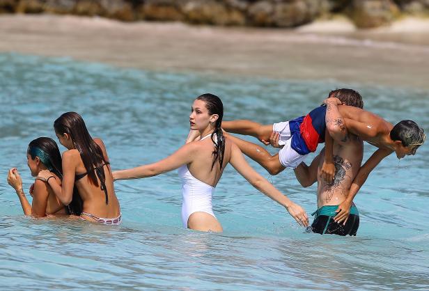 Bella Hadid und andere Personen verbringen Zeit im türkisfarbenen Wasser eines Strandes.
