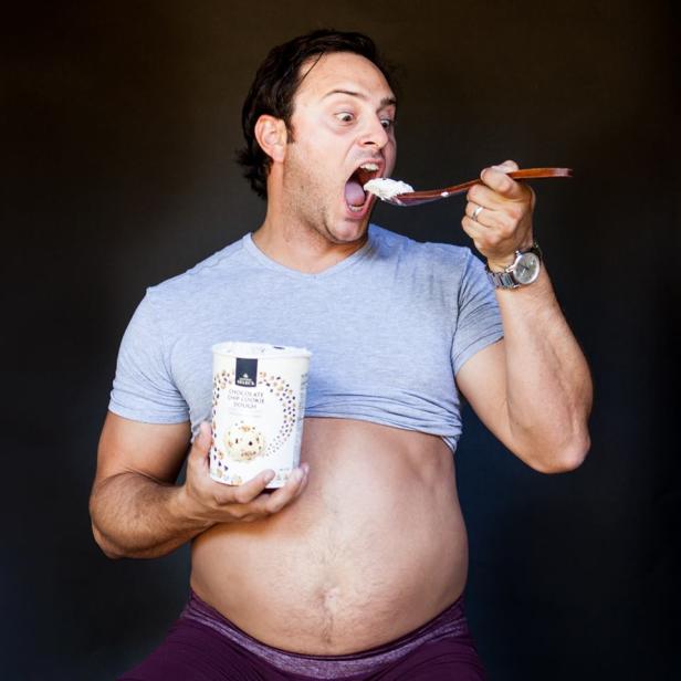 Ein Mann isst mit einem Löffel Eiscreme direkt aus einem Becher „Chocolate Chip Cookie Dough“.