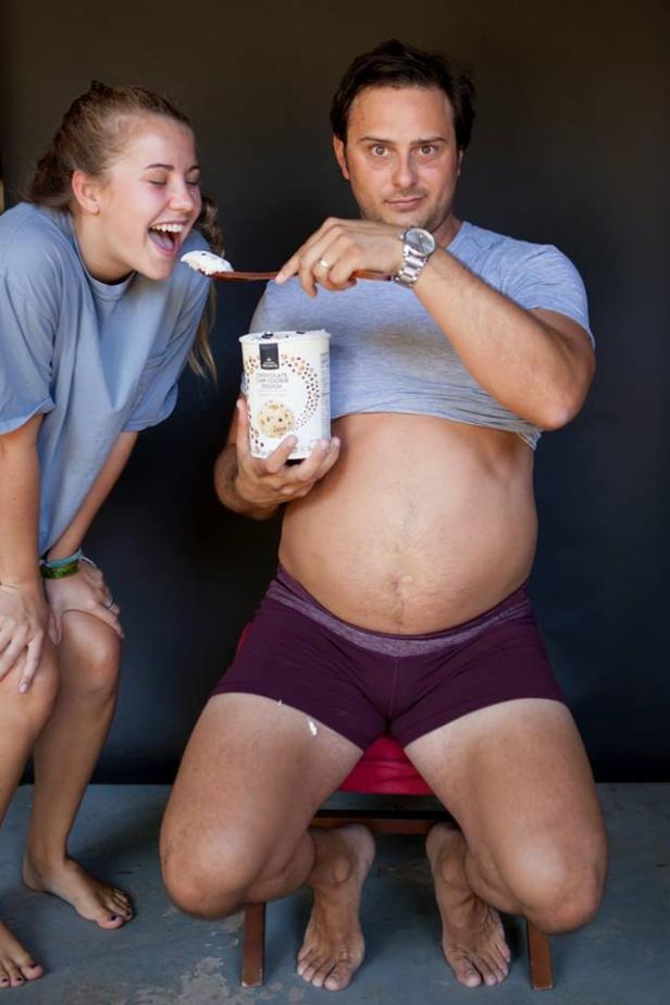 Ein Mann mit Bauch isst Eis, während eine Frau daneben lacht.