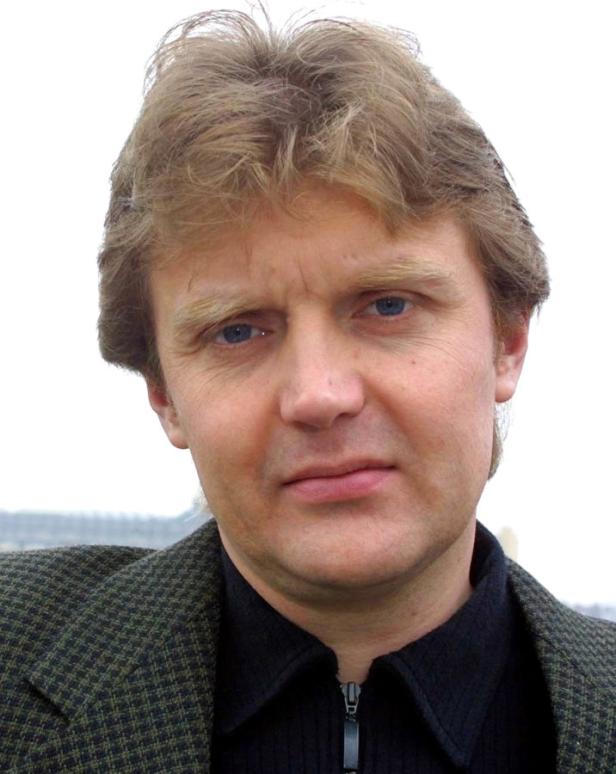 Porträt eines Mannes mit blonden Haaren und blauem Blick.